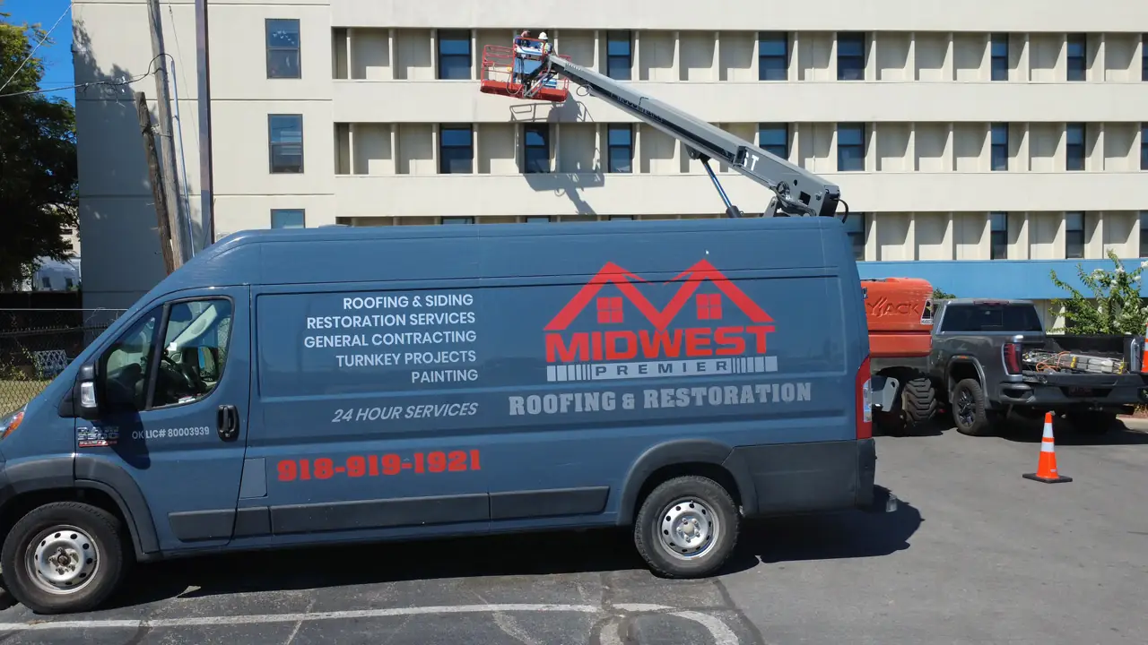 A Midwest Premier Roofing van on a commercial job site with crews working from a boom lift